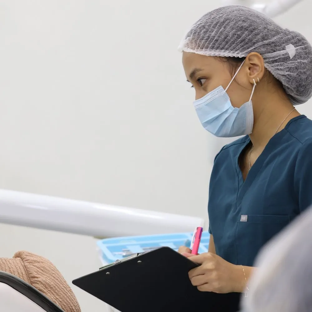 MDN dentist listening to a patient and taking notes during a consultation